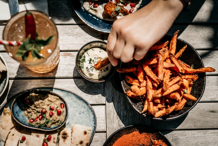 a restaurant patron dips fries into a sauce