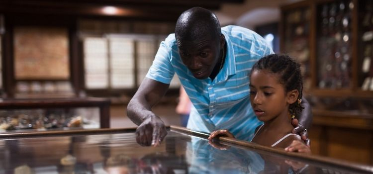 African American father and daughter looking at stands with exhibits at historical museum