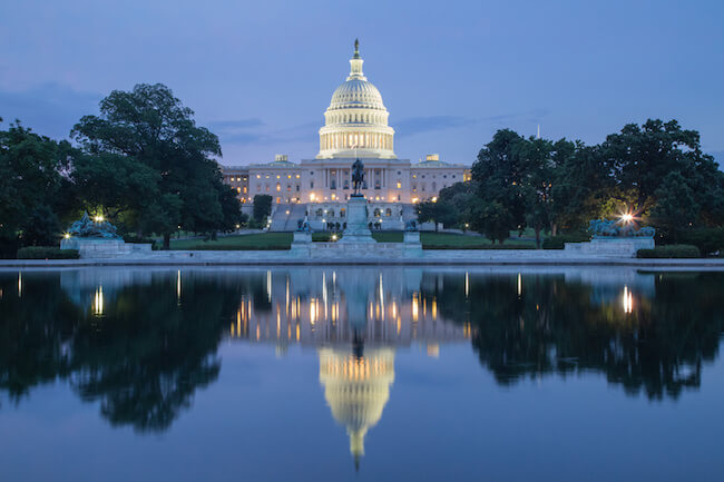 a view of the US capitol building at dusk across the reflecting pool