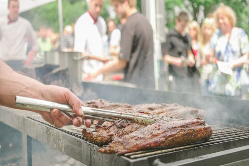 a contestant flips meat on a hot grill during the national capital giant barbecue battle