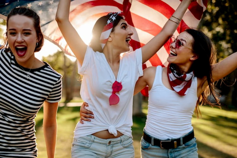 friends hold an american flag and smile during an independence day celebration