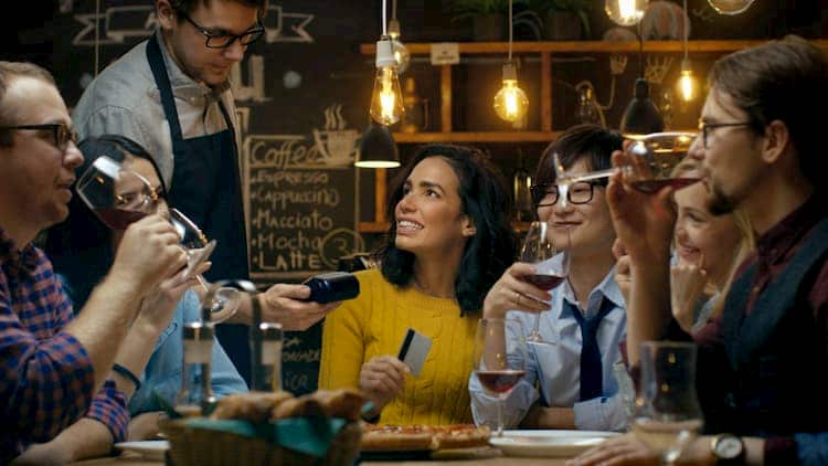 Woman using credit card to pay for casual meal with friends