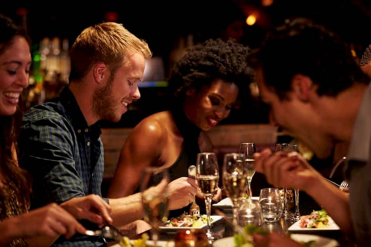 Group of diverse young friends eating dinner