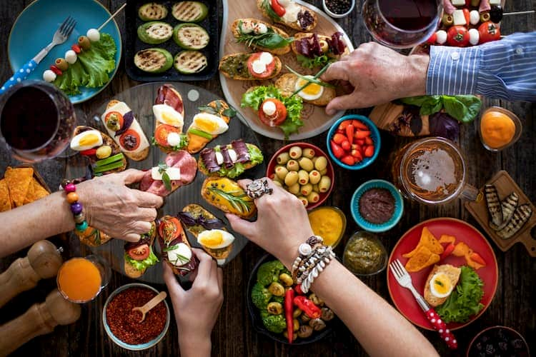 People's hands reaching for plates of tapas