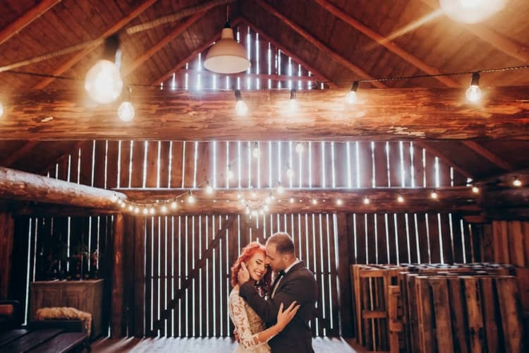 A couple is dancing at a barn wedding