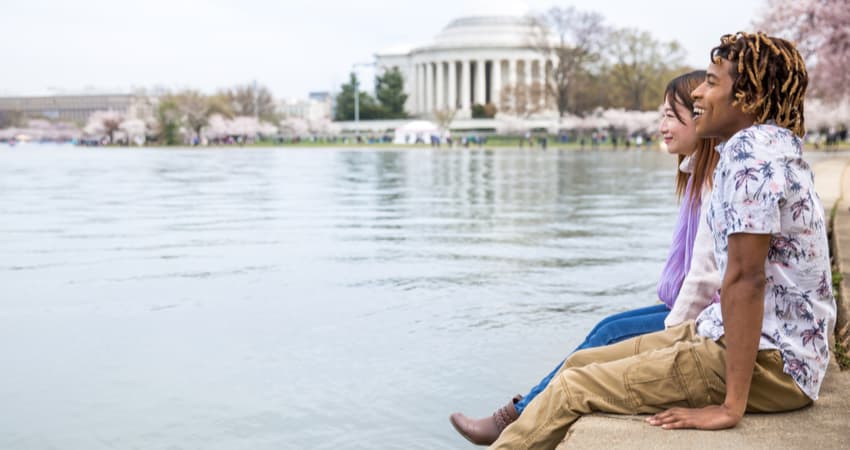 Two people sitting along the Tidal Basin in Washington DC