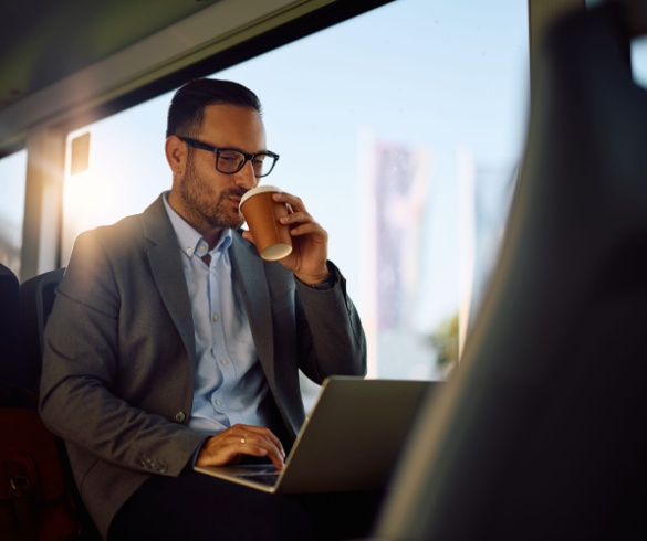 A man works on his laptop while riding in a charter bus to work