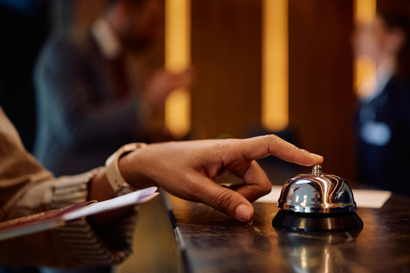 a man rings a bell at the concierge desk of a hotel